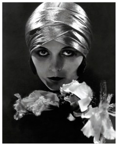 Actress Pola Negri wearing a lam� headwrap, with flowers in front of her